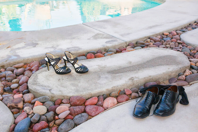 Brides shoes and grooms shoes and socks discarded next to the pool