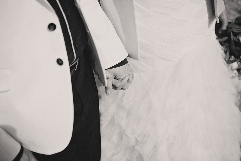 Black and white detail of bride and groom holding hands