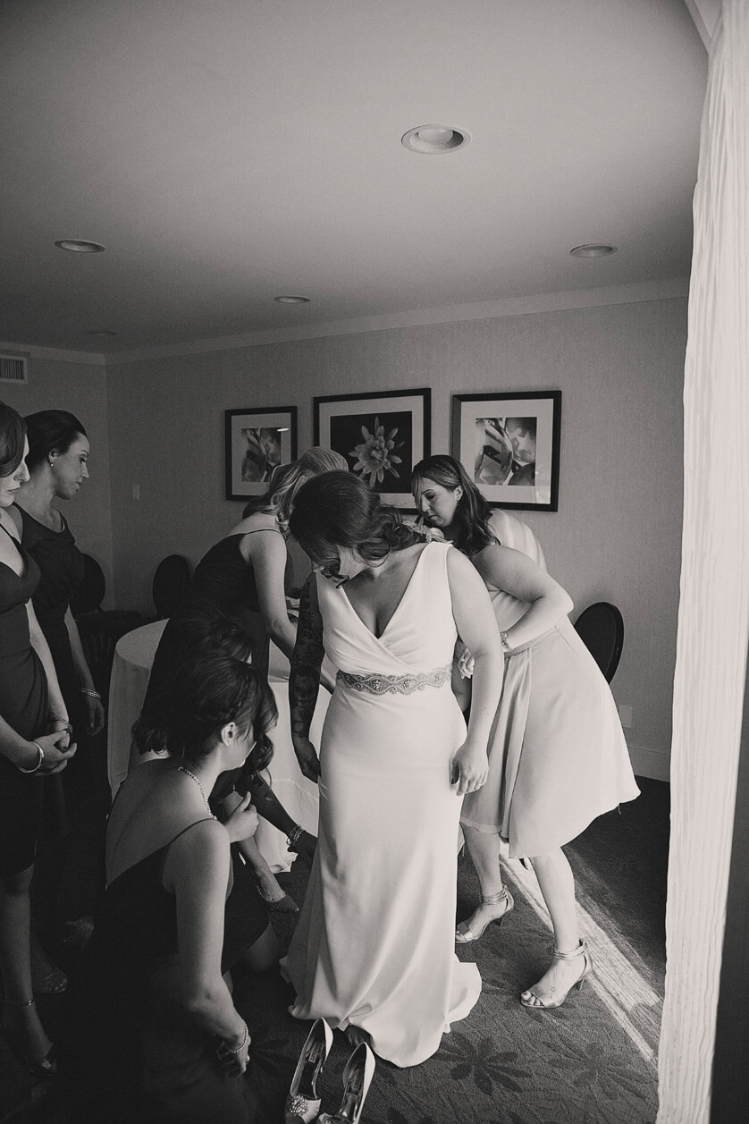A lovely black and white image of the the bridesmaids helping the bride with her dress