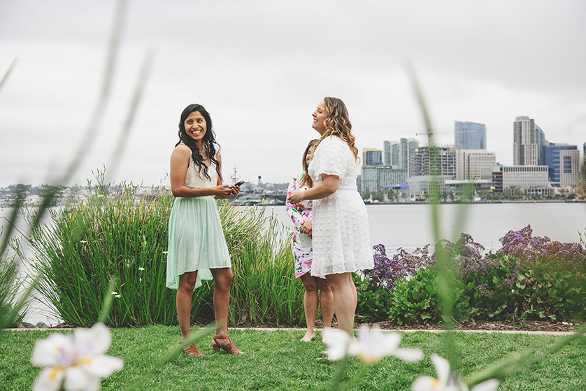 The two brides enjoy a humorous moment during their ceremony at a waterfront park in San Diego 