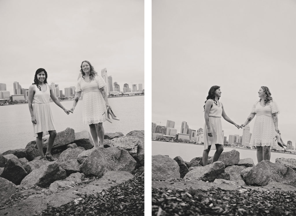 The newlywed couple pose for fun portraits on the rocks with the San Diego skyline and bay in the background