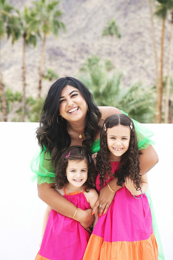 Auntie and nieces pose smiling in colorful dresses