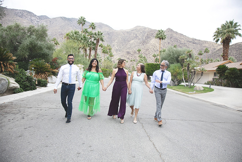 Grandparents stroll down the road with their adult kids, chatting and interacting