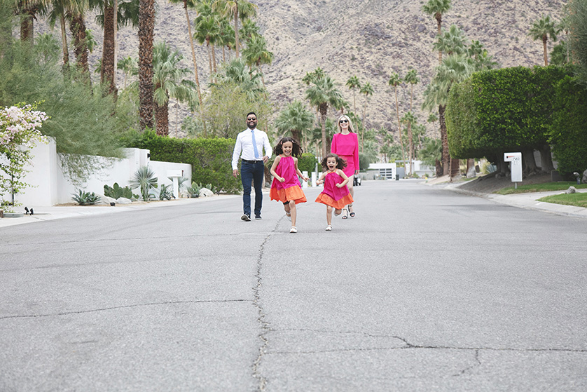 Parents stroll towards the camera with two young girls running out in front