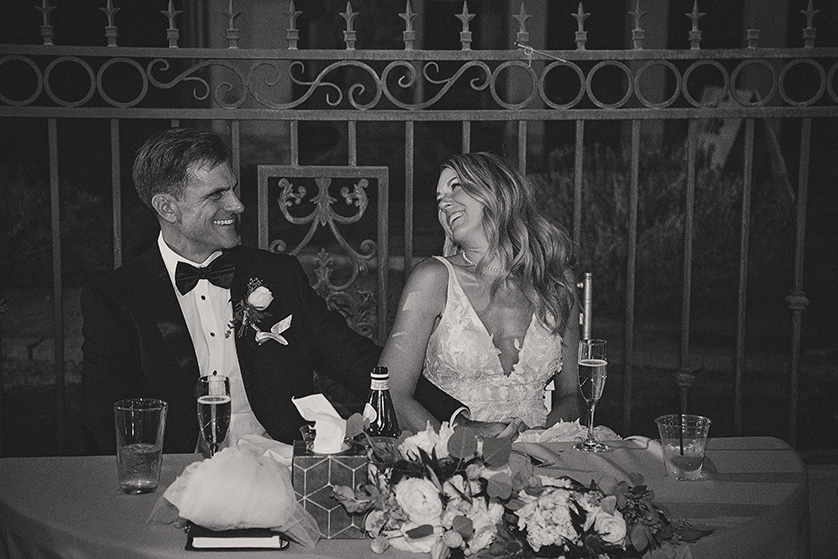 The couple at their sweetheart table laugh at speeches