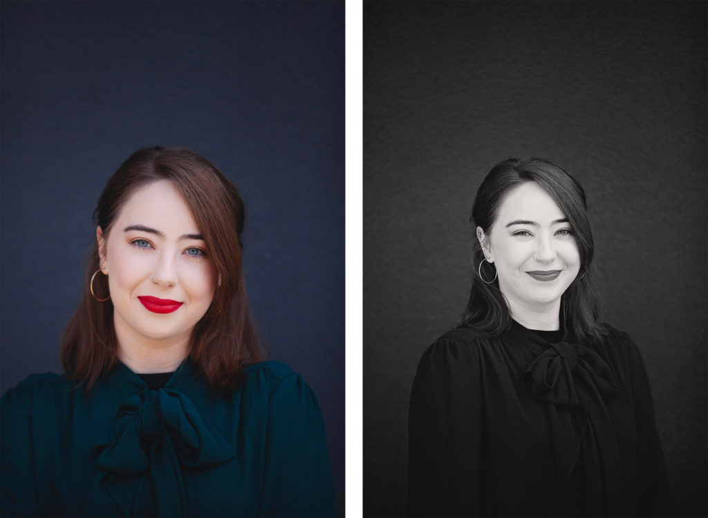 Young woman with dark hair, red lipstick, and a dark blouse posing against a dark background.