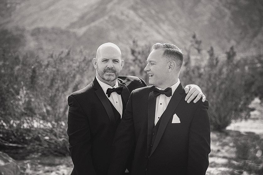 Sweet portrait of two grooms embracing in the desert of Palm Springs