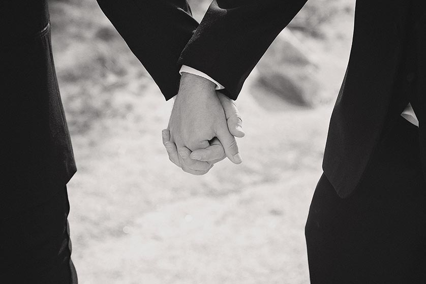 Black and white photograph of two grooms holding hands