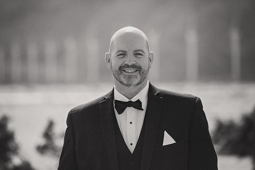 Portrait of a groom wearing a tux and bowtie standing in front of the Palm Springs Wind turbines