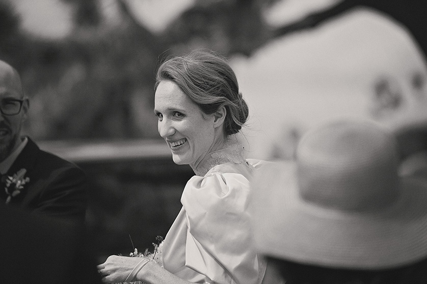 A candid black and white photograph of the bride smiling at someone off camera