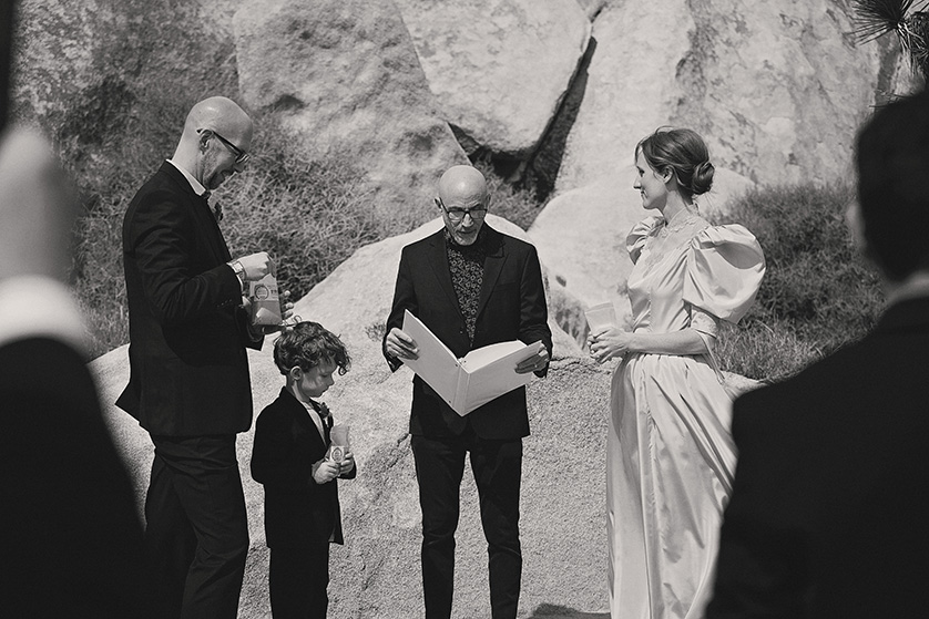 The couple stand with their officiant and young son at the ceremony site at Cap Rock, Joshua Tree Ca. 