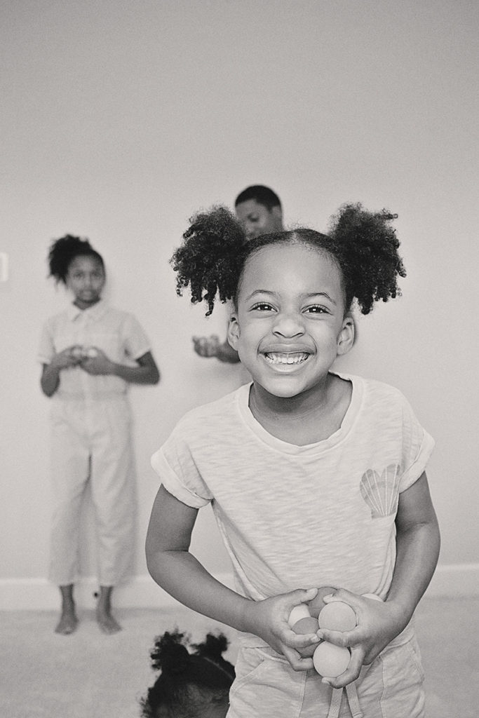 Young girl with pig tails smiles widely at the camera.