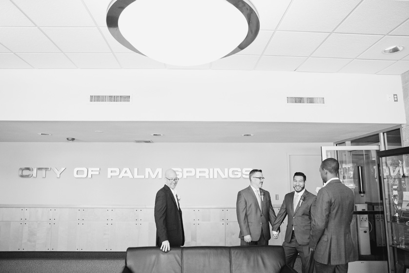 Palm Springs city hall elopement photograph in black and white, the same-sex couple reflect happily with their two friends in attendance.