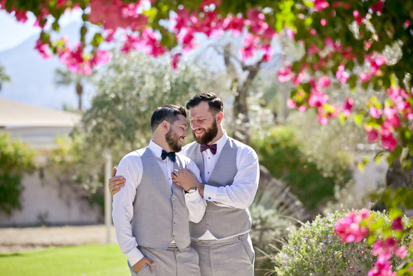 Grooms snuggling in a lush garden