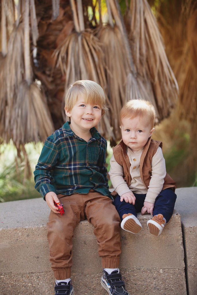 Two young brothers sit on a bench in the park