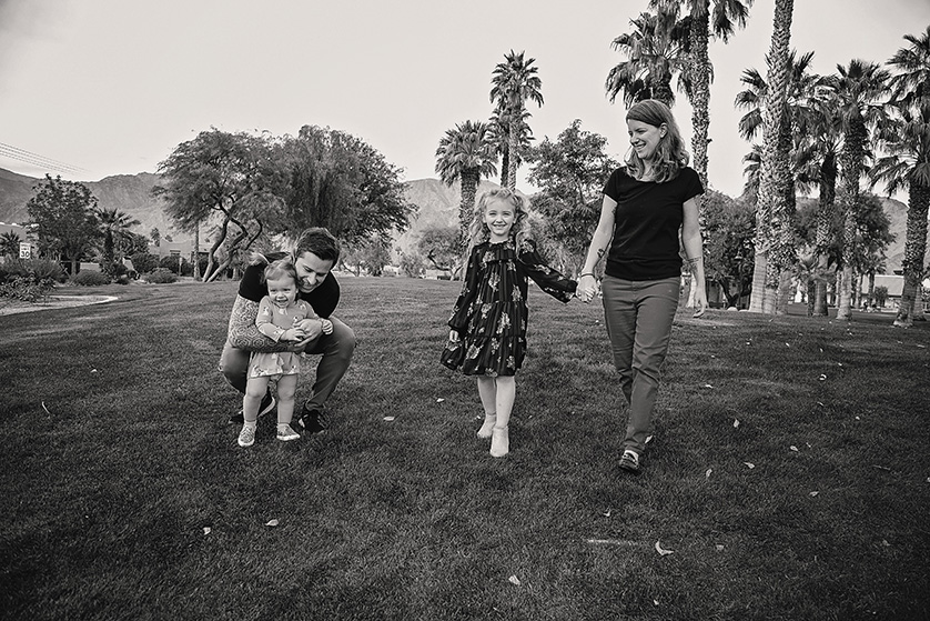 Candid photograph of two parents and their two young daughters at a park