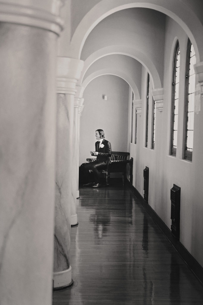 Groom sits at the end of a long hallway