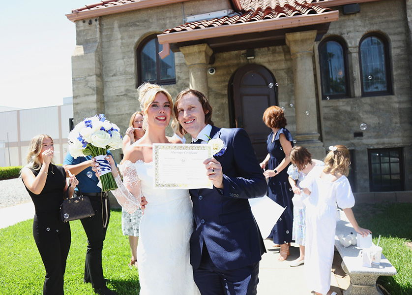 bride and groom happily show off their marriage certificate