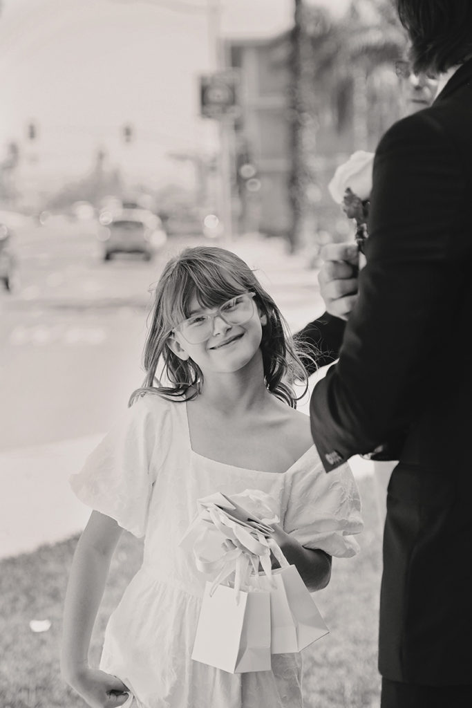 Young girl with bangs and glasses smiles sweetly at the camera