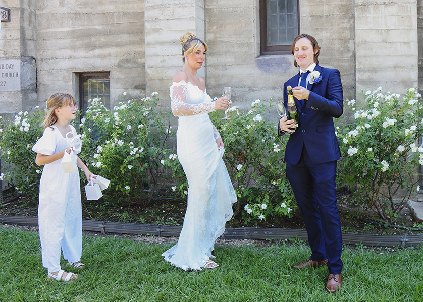 Bride and groom pop open a bottle of champagne