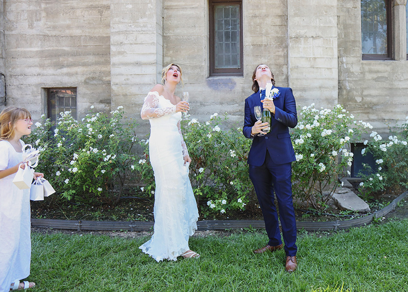 Bride and Groom delight at the flying cork from a champagne bottle