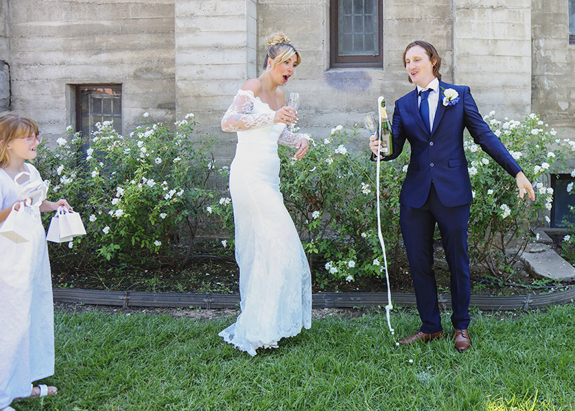 Bride and groom with champagne bottle outside a church