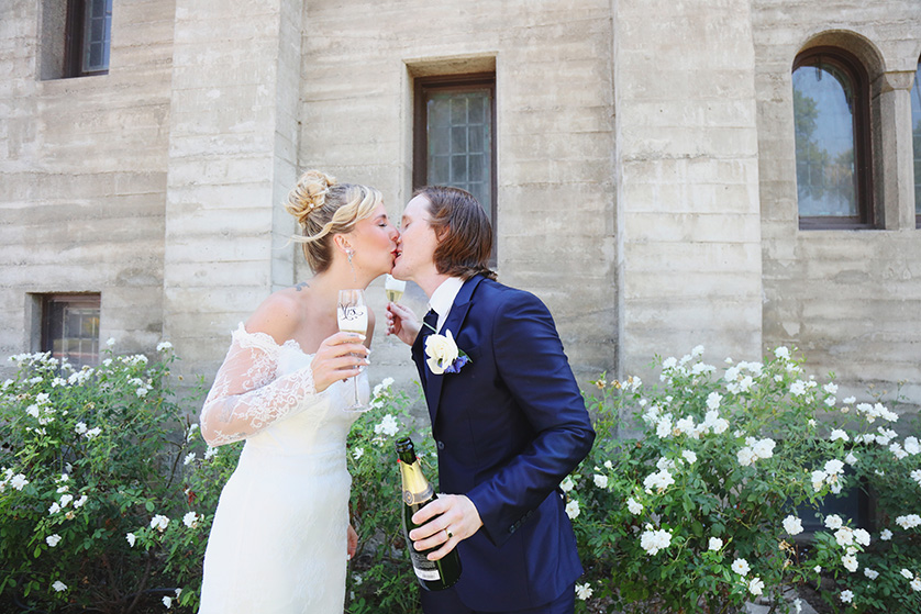 bride and groom celebrate with a kiss and champagne