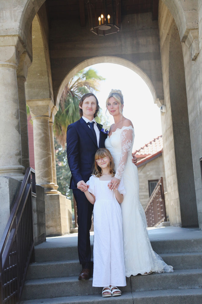 Bride and Groom pose with a young girl on church steps