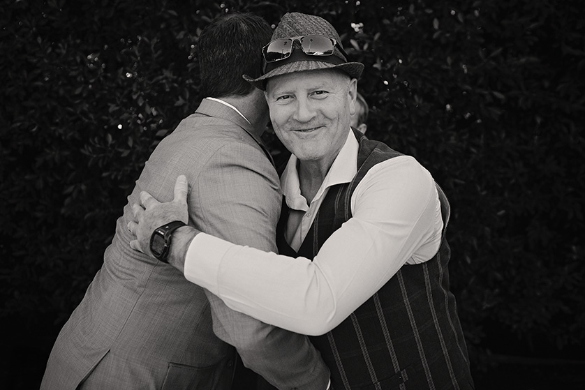 Groom embraces a guest during a joyful moment at a Palm Springs backyard wedding.