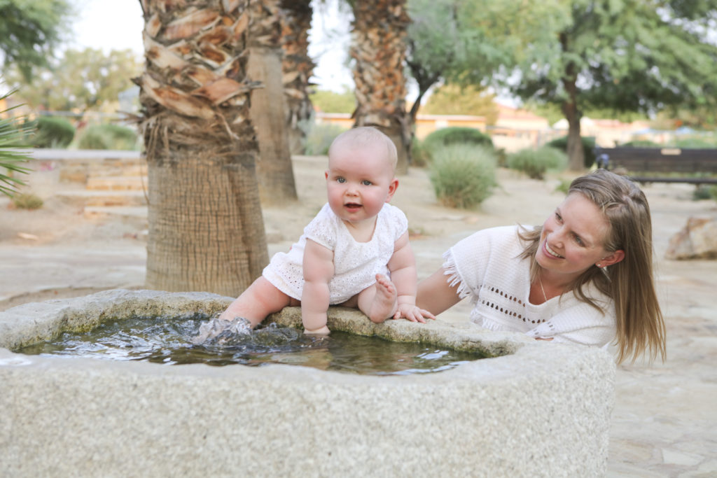 Mother with baby girl dipping her feet in a pond