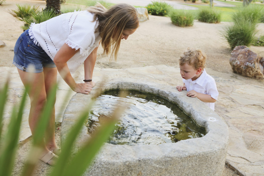 Mom and her son look curiously into a pond