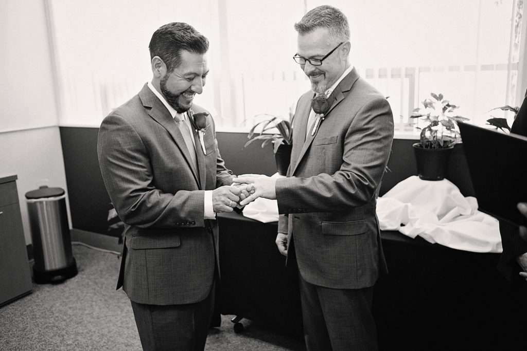 Two grooms exchange wedding rings during an intimate Palm Springs City Hall elopement ceremony.