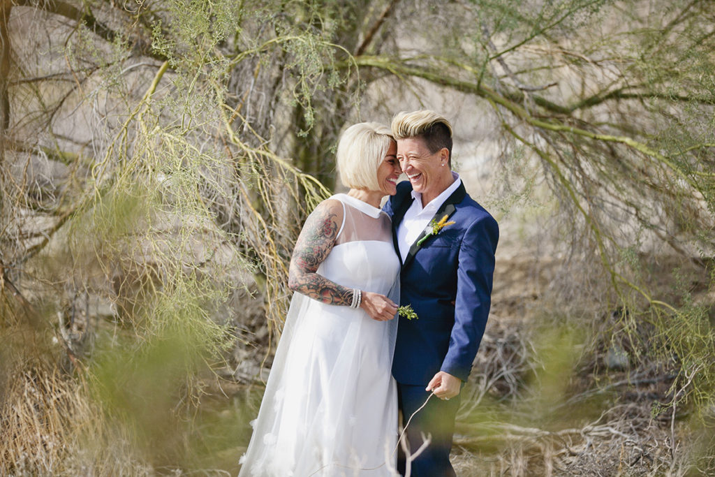 Two brides share a joyful embrace during their Palm Springs desert elopement.