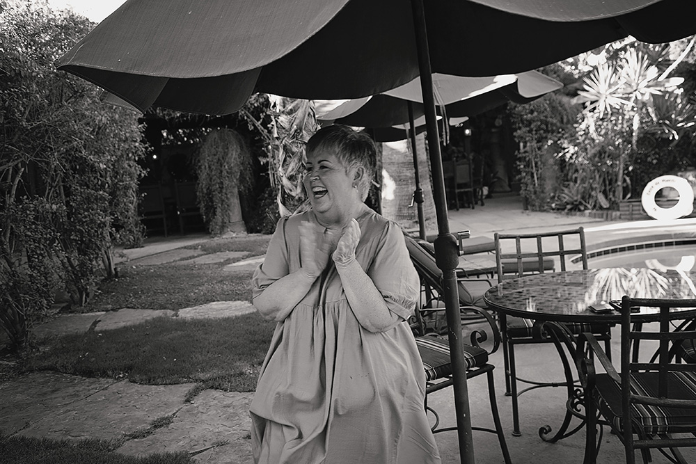A woman laughs with joy and claps her hands while celebrating a surprise proposal at Casa de Monte Vista in Palm Springs.