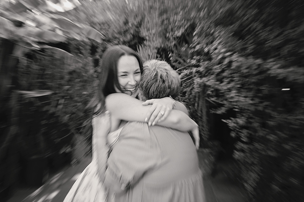A woman beams with happiness while hugging a loved one after a surprise proposal at Casa de Monte Vista in Palm Springs.