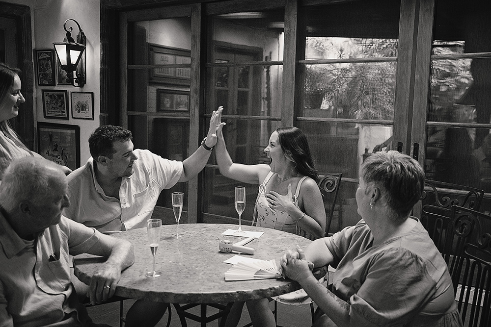 A newly engaged woman shares a joyful high five with a guest while celebrating her surprise proposal at Casa de Monte Vista in Palm Springs.