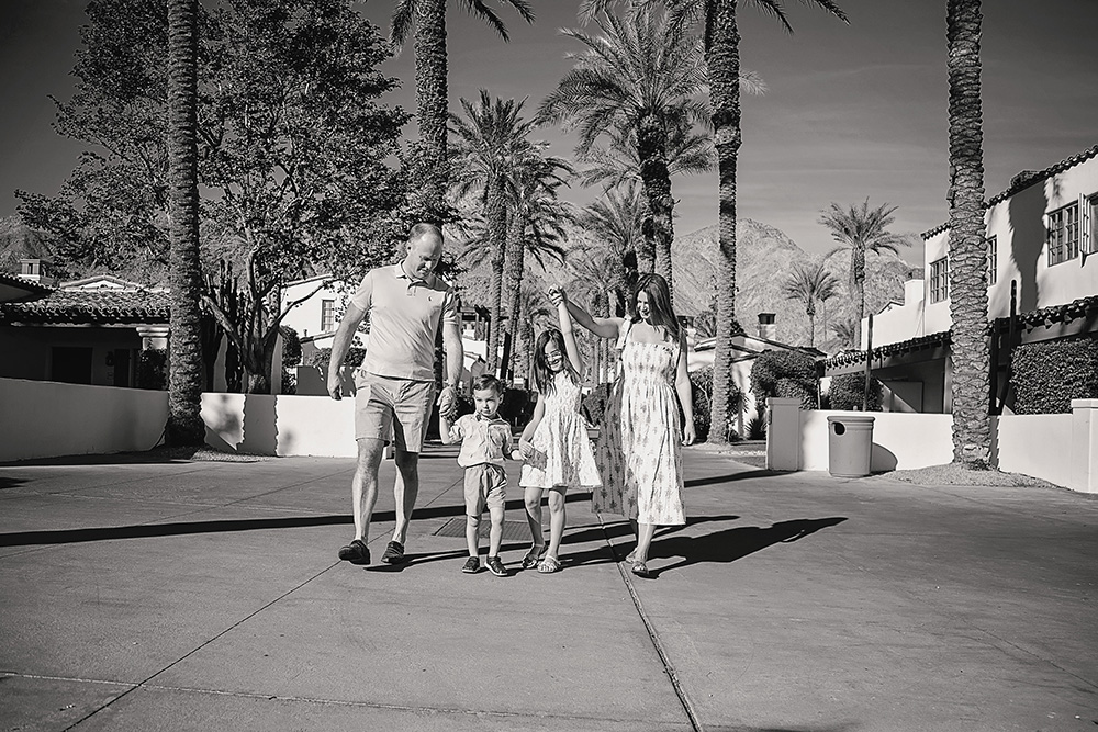 Family photographed in black and white walking happily towards the camera