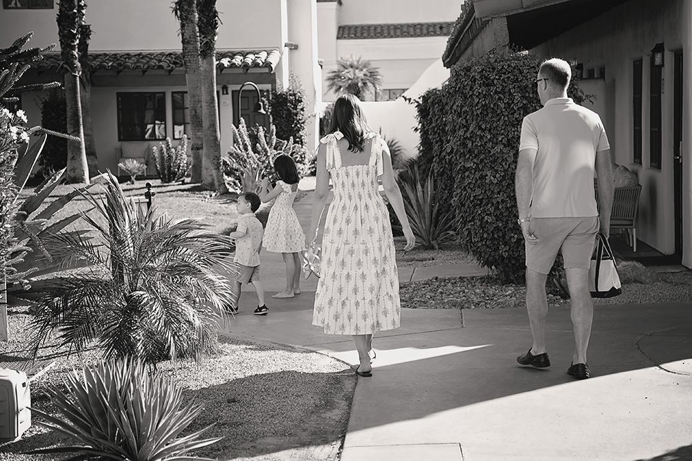 A candid black and white photograph of a family of four meandering through garden grounds