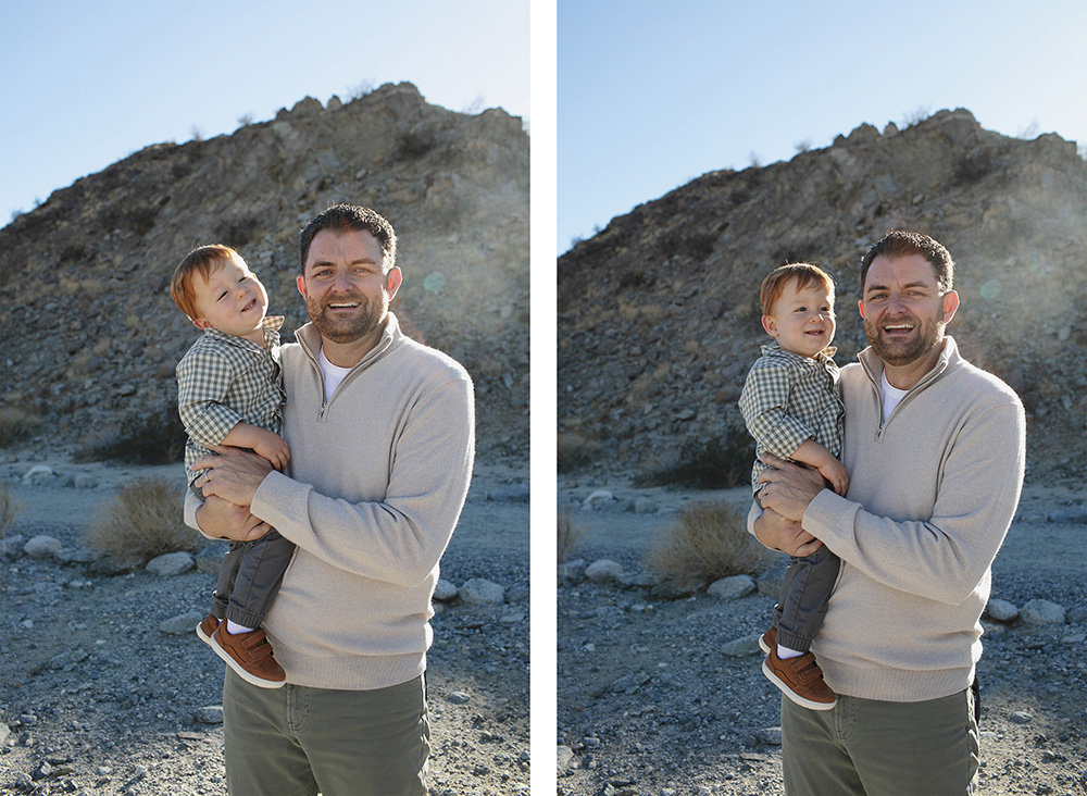 “Father holding his young son during a family photo session in La Quinta, California. They stand in front of a rocky desert hillside with bright morning sunlight glowing behind them.”