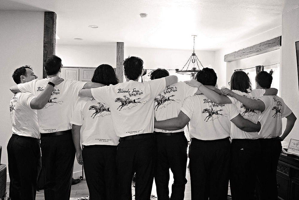 Groomsmen wearing personalized wedding T-shirts while getting ready at Bubbling Wells Ranch, captured in black and white documentary wedding photography