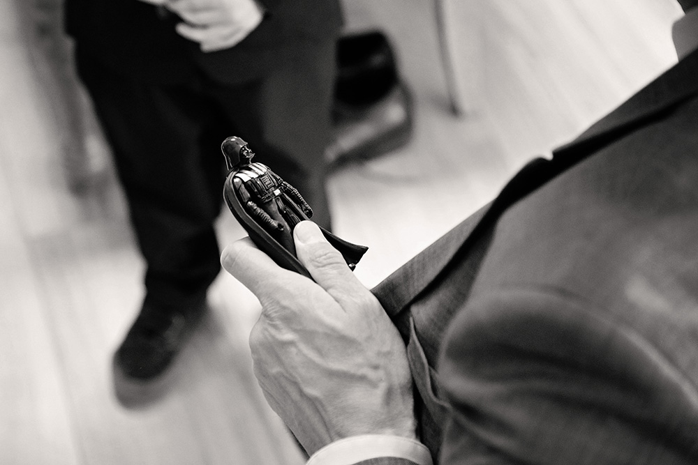 Close-up of groom holding a small figurine during wedding preparations at Bubbling Wells Ranch, captured in black and white documentary wedding photography
