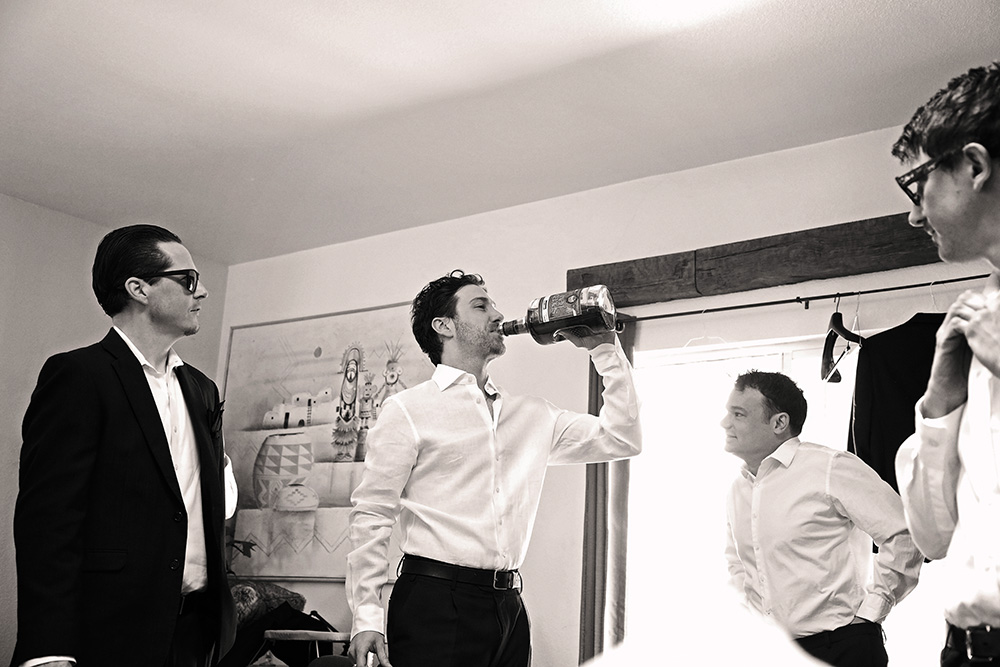 Groom sharing a relaxed moment with groomsmen while getting ready at Bubbling Wells Ranch, captured in black and white documentary wedding photography