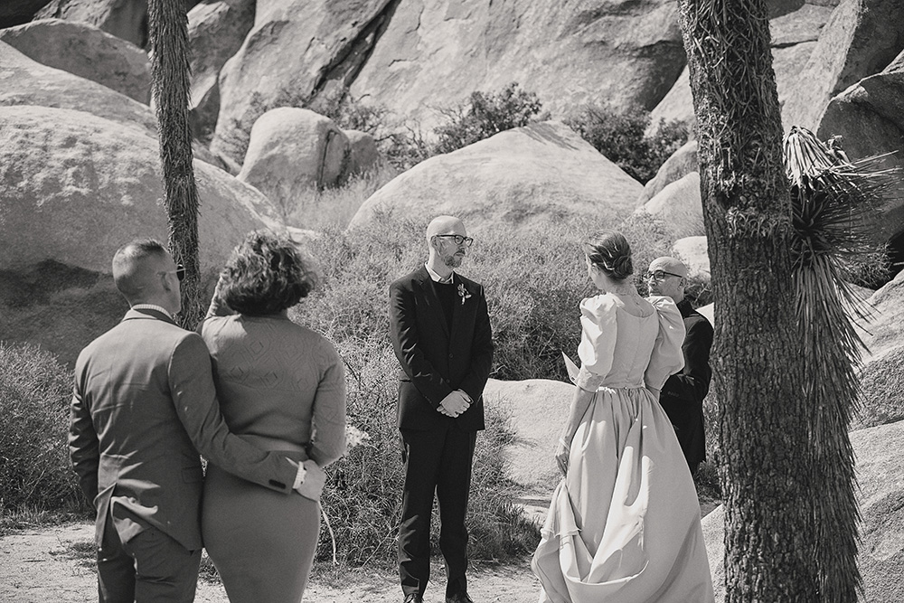 Small, intimate wedding ceremony among boulders at Joshua Tree National Park, captured in black and white documentary wedding photography