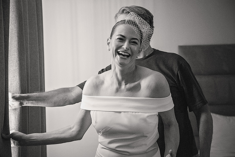 Bride laughing in her wedding dress during an intimate boutique hotel wedding at Skylark Hotel, captured in black and white documentary wedding photography