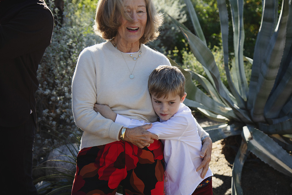 Young boy hugging his grandmother during a candid Palm Springs family photography session, surrounded by desert plants.