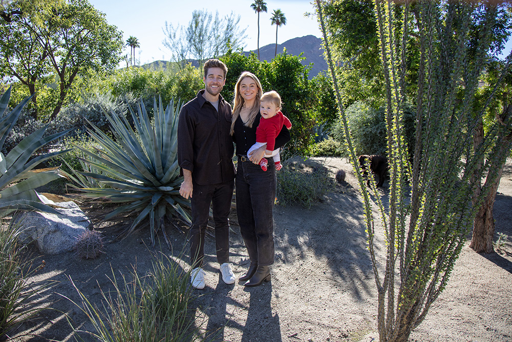 Palm Springs family photo of parents holding their baby during a relaxed outdoor session surrounded by desert plants and palm trees in California