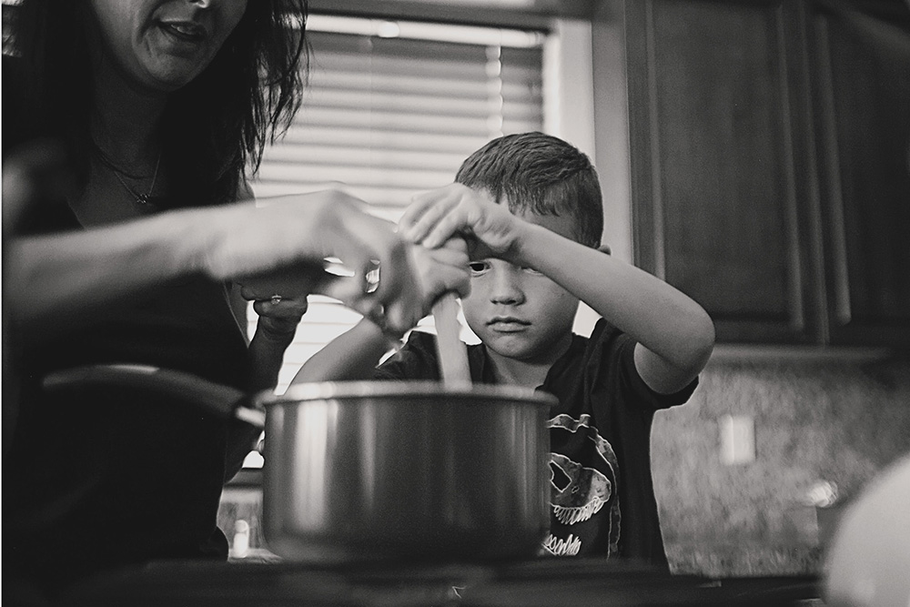 Mother and son stirring a pot together in the kitchen during a documentary day in the life family photo session.
