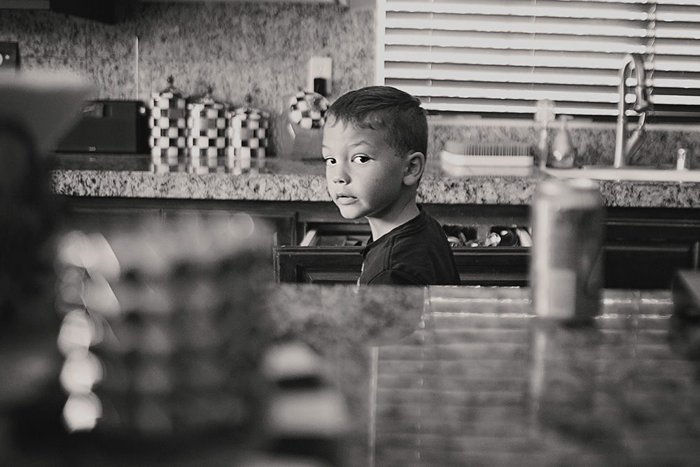 Young boy glancing toward the camera in the kitchen during a documentary day in the life family photo session.
