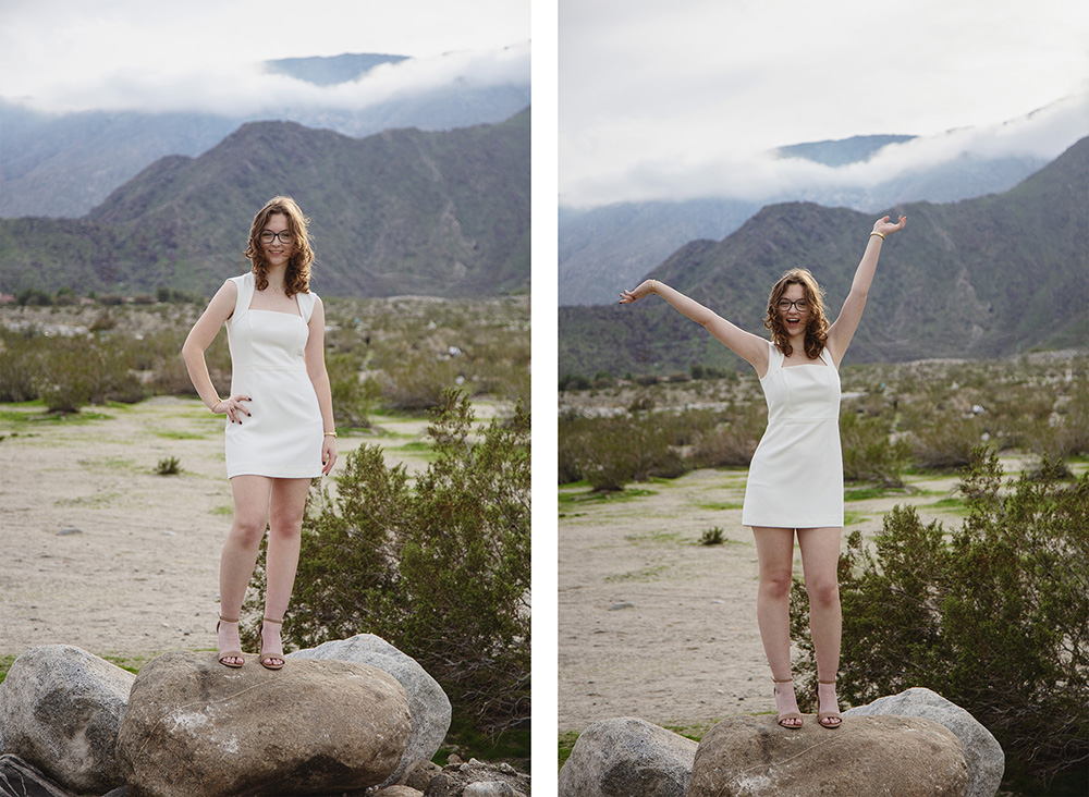 High school senior stands on a rock smiling and celebrating