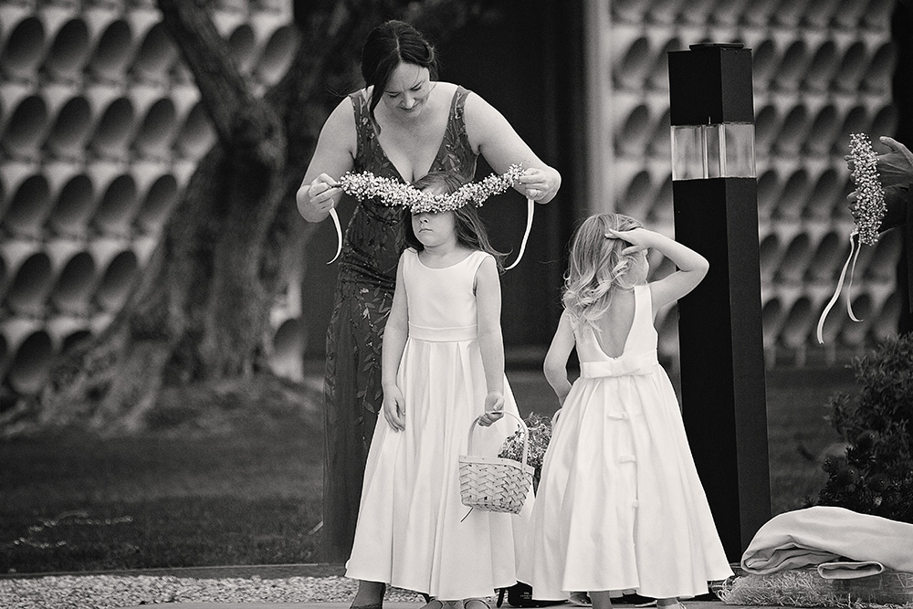 A documentary style capture of two flowers girls having their flower crowns placed on their heads